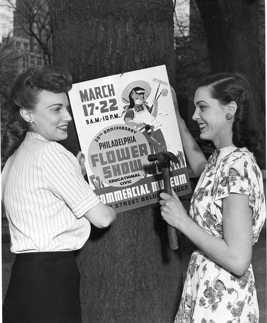 Flower show presenters hang up a poster promoting the 1947 Philadelphia Flower Show.