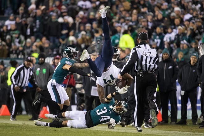 Eagles' Cre'Von LeBlanc (34) and Marcus Epps (37) flip Seattle's DK Metcalf (14) out of bounds Sunday at Lincoln Financial Field.