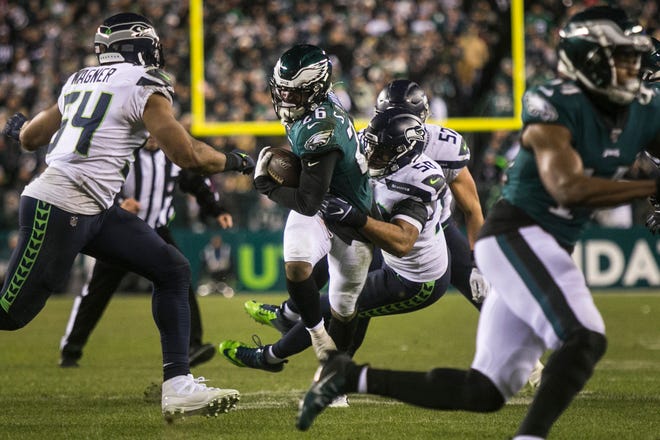 Eagles' Miles Sanders (26) is wrapped up by Seattle's K.J. Wright Sunday night at Lincoln Financial Field. The Seahawks defeated the Eagles ending their season 17-9.